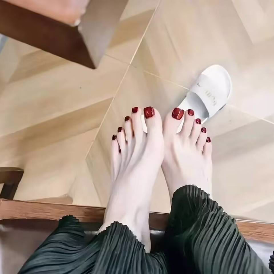 Luxury Toe Nail Trends featuring intricate gold foil accents, shimmering pearl embellishments, and a deep crimson ombré on perfectly pedicured toes.
