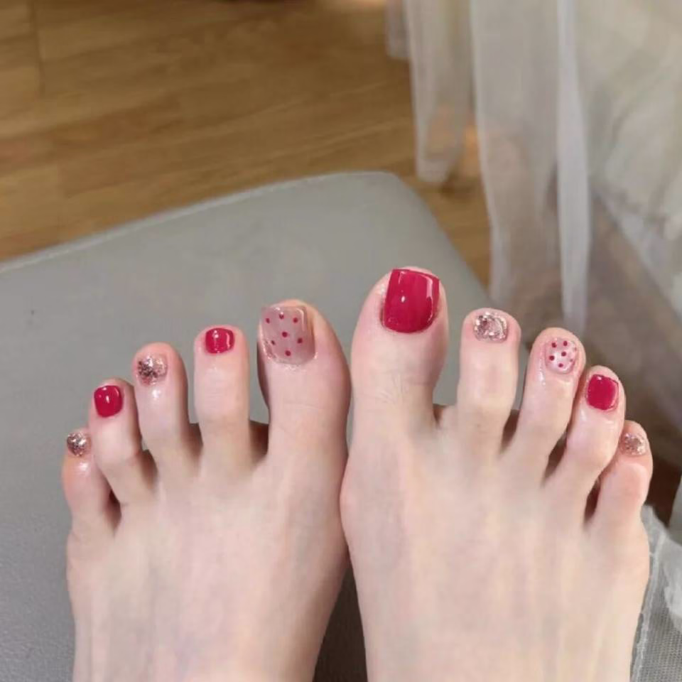  Close-up view of whimsical fairy pedicure designs featuring delicate glitter gradients, tiny floral accents, and ethereal wing motifs on toenails, in soft pastel and iridescent colors.
